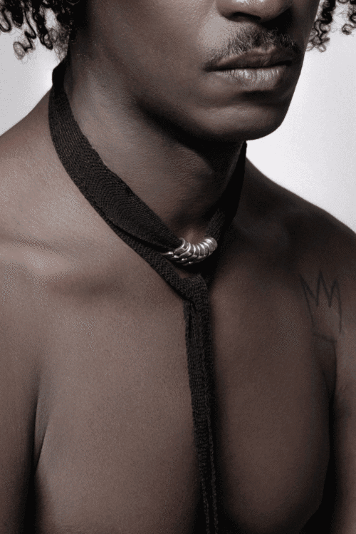 homme de face avec top en maille et accessoire maille et bijoux en argent